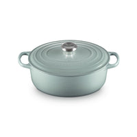 Casserole en fonte émaillée céleste avec couvercle et anses, surface légèrement ondulée et poignée centrale en métal.