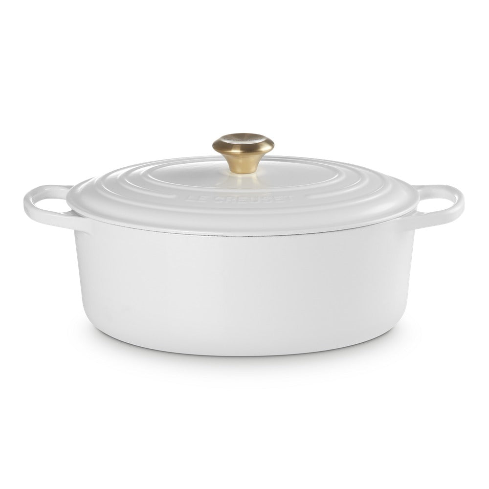 ovaal braadpan wit van gietijzer met gouden handgreep en deksel, glad en glanzend oppervlak, neutrale setting.