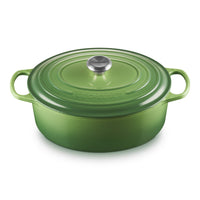 ovaal braadpan groen met deksel en handgrepen, realizzata van geëmailleerd gietijzer, op witte achtergrond.