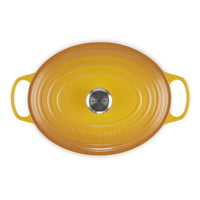 ovaal braadpan van keramiek geel met handgrepen, glanzende afwerking en logo LE CREUSET al centro.