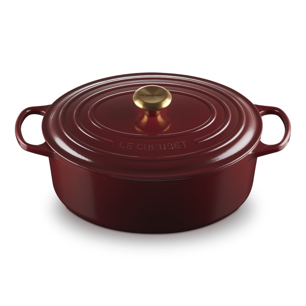 Ronde braadpan in rood met deksel, gouden handgreep en motivi circolari sulla oppervlak.