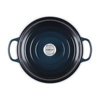 Casseruola rotonda in ceramica blu scuro con manici, logo centrale "LE CREUSET" e superficie liscia.