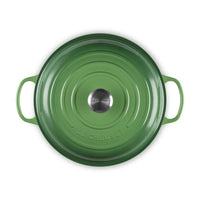 Casseruola rotonda verde con manici, in ghisa smaltata, con fondo e logo "LE CREUSET" al centro.