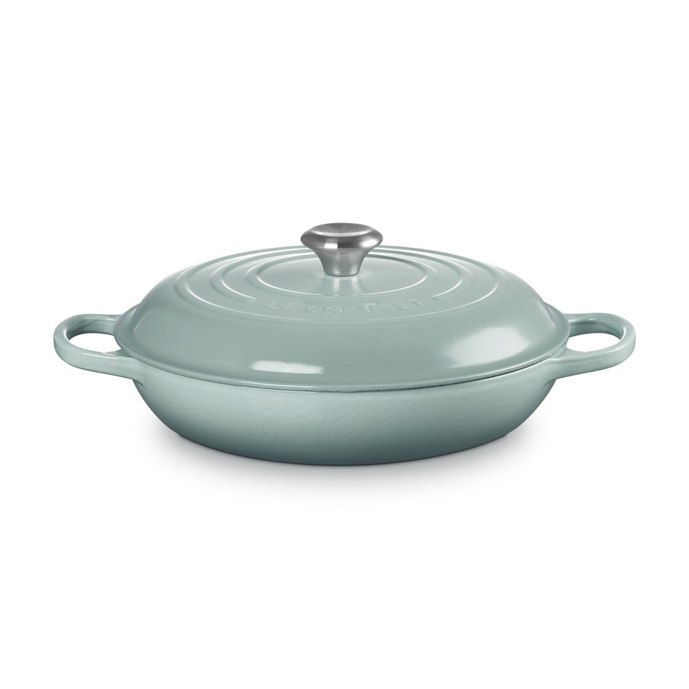 Casseruola ovale in ghisa smaltata di colore verde acqua, con coperchio e maniglie laterali.