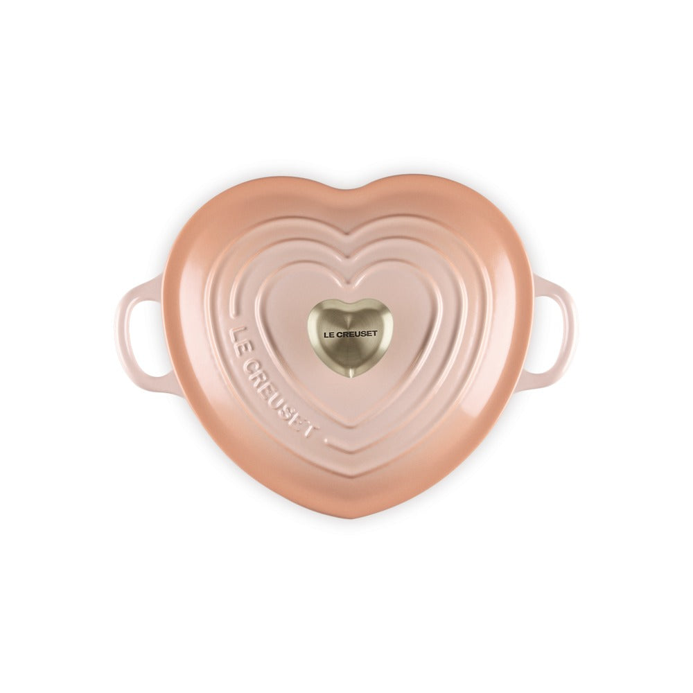 Cacerola en forma de corazón, color rosa, con dos asas y logo dorado "Le Creuset" en el centro.
