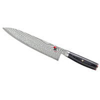 coltello da cucina con lama lunga in acciaio damasco e manico nero in legno liscio su sfondo bianco