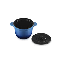 Casserole en céramique bleue avec anses, couvercle noir en métal à côté, surface lisse et brillante.