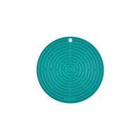 Sottopentola circolare di silicone di colore turchese con motivo a labirinto, presente uno spazio per appendere. Fondo bianco.