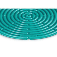 Tapis circulaire en silicone turquoise à motif spiralé, logo "LE CREUSET" en bas.