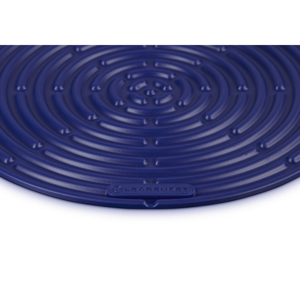 Tapis rond en silicone bleu à motif spiralé et surface lisse, logo LE CREUSET visible.