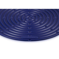 Tapis rond en silicone bleu à motif spiralé et surface lisse, logo LE CREUSET visible.