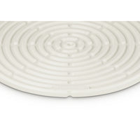 Tapis en silicone blanc à surface spiralée et logo “LE CREUSET” visible.