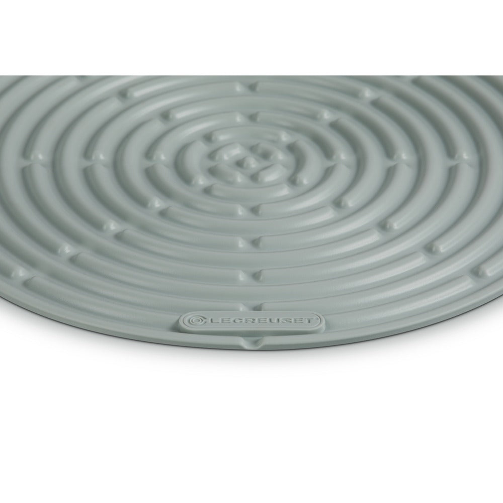 Tapis circulaire vert clair à motif spiralé, en matériau synthétique, avec logo LE CREUSET.