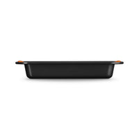Black rectangular baking tray with raised edges and orange handles, on white background.
