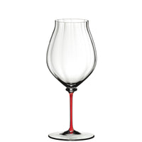Calice à vin transparent avec pied fin de couleur rouge, sur fond blanc.