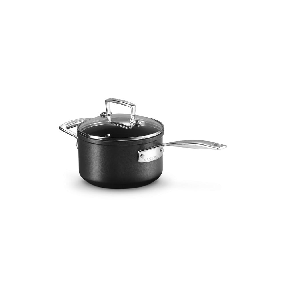 Casseruola nera con manici in acciaio inox e coperchio trasparente, appoggiata su sfondo bianco.
