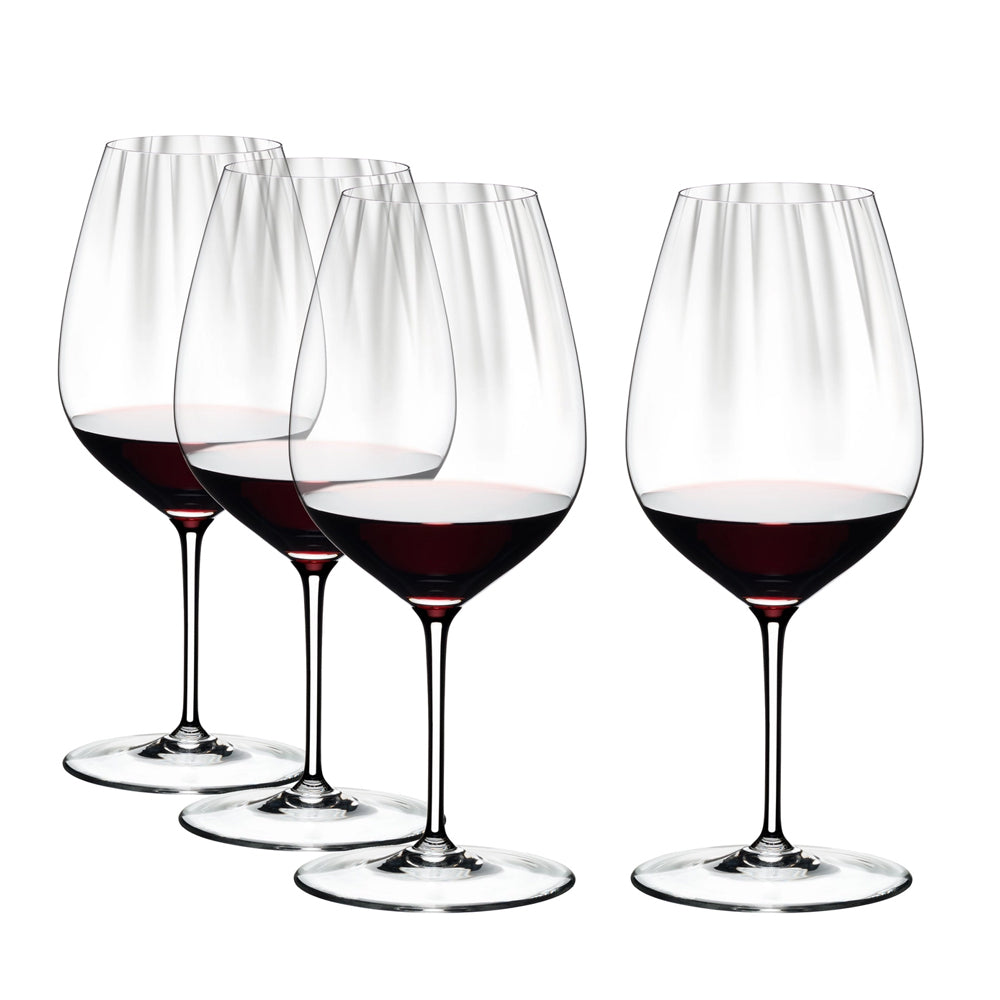 Four transparent glass glasses with red wine poured to one third, white background
