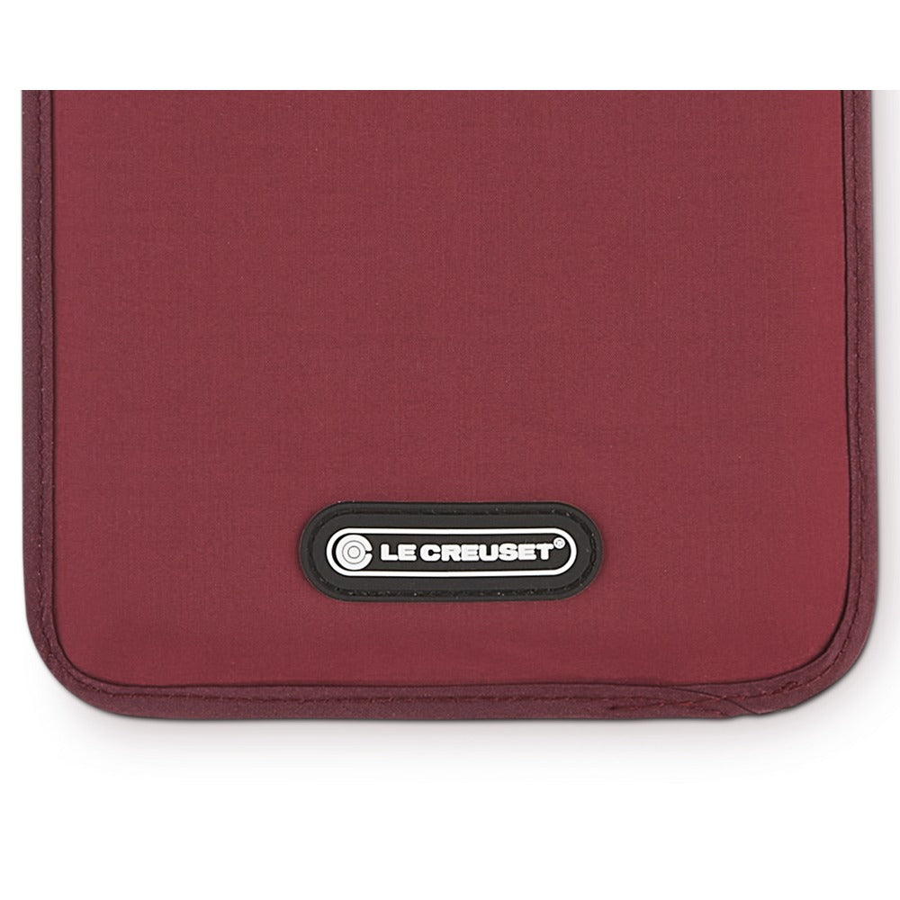 Burgundy fabric placemat with black "LE CREUSET" logo on the side.