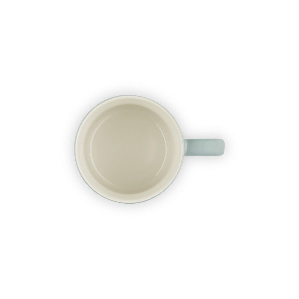 Tazza in ceramica color crema con manico azzurro, vista dall'alto, senza contenuto all'interno.