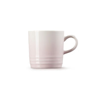Tazza in ceramica, colore rosa chiaro con manico, superficie liscia e decorazione a righe sul fondo.