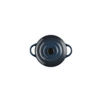 Dark blue enamelled ceramic saucepan with two handles and central hole. Glossy surface and visible "Le Creuset" logo.