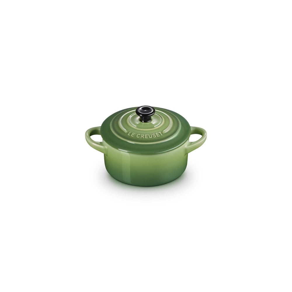Green ceramic saucepan with lid and handles, glossy surface, "Le Creuset" logo present. Round bottom.
