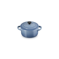 Round ceramic casserole blue with handles, black lid and details glossy, placed on white background.