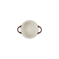 Round casserole with edges burgundy and handles, interior white satin, on white background.