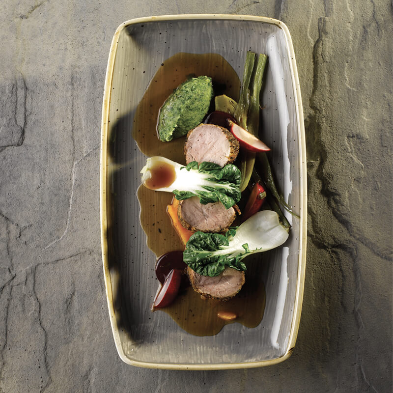 Plato elegante con carne en rodajas, verduras coloridas y salsa oscura en un cuenco gris. Ambiente minimalista y refinado.