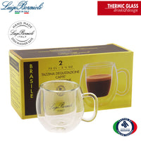 Transparent double-wall espresso cup with glass handle in front of yellow box with cup design and text in