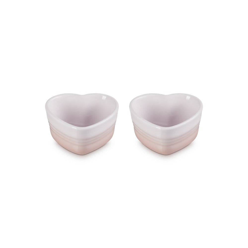 Dos cuencos en forma de corazón, en tonos rosa claro y blanco, con acabados brillantes y estrías horizontales.