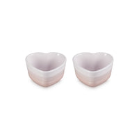 Dos cuencos en forma de corazón, en tonos rosa claro y blanco, con acabados brillantes y estrías horizontales.
