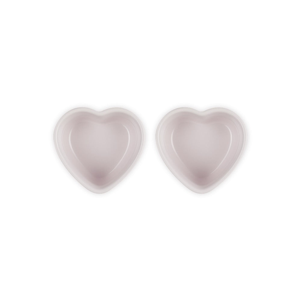 Dos cuencos en forma de corazón, en rosa claro, con acabado liso y brillante, colocados juntos sobre fondo blanco.
