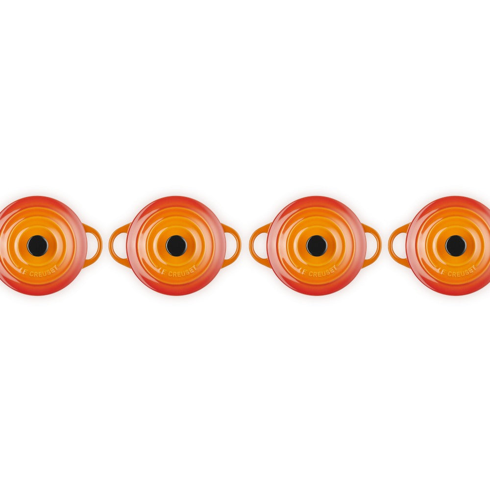 Set de petites casseroles rondes en céramique émaillée, couleur orange et rouge, avec poignées et fond noirs, disposées en rangée.