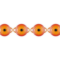 Set de petites casseroles rondes en céramique émaillée, couleur orange et rouge, avec poignées et fond noirs, disposées en rangée.