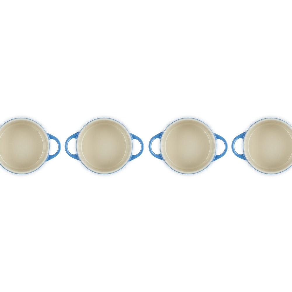 Casseroles rondes avec anses bleues et intérieur clair, disposées en rangée sur fond blanc.
