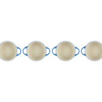Casseroles rondes avec anses bleues et intérieur clair, disposées en rangée sur fond blanc.