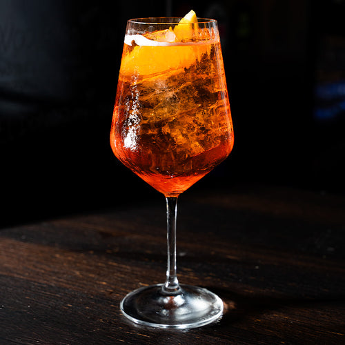 Transparenter Glasbecher mit Cocktail orange und Eis, garnished mit an orange slEis, auf Holztisch scuro.
