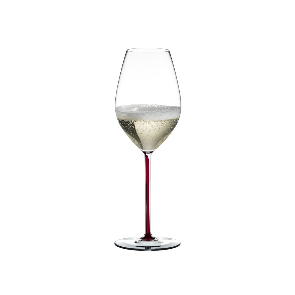 Copa de vino transparente con tallo rojo, que contiene un líquido espumoso de color claro. Fondo blanco.
