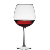 Calice di vetro trasparente con vino rosso riempito fino alla metà, sfondo bianco uniforme.