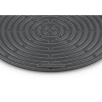 Tapis rond gris foncé à motif spiralé et logo "LE CREUSET" en bas.