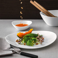 White plate with green romaine cabbage salad, orange pumpkin slice and walnuts, orange sauce in