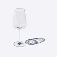 Verre transparent en verre, haut et élancé, avec base ronde et ombre projetée en spirale. Fond clair.