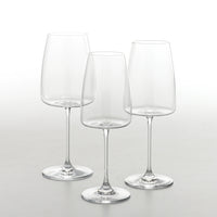 Trois verres en verre transparent, à longue tige et large base, disposés sur fond clair.