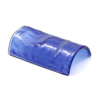 Elemento curvo de cerámica esmaltada azul con reflejos brillantes sobre fondo blanco.