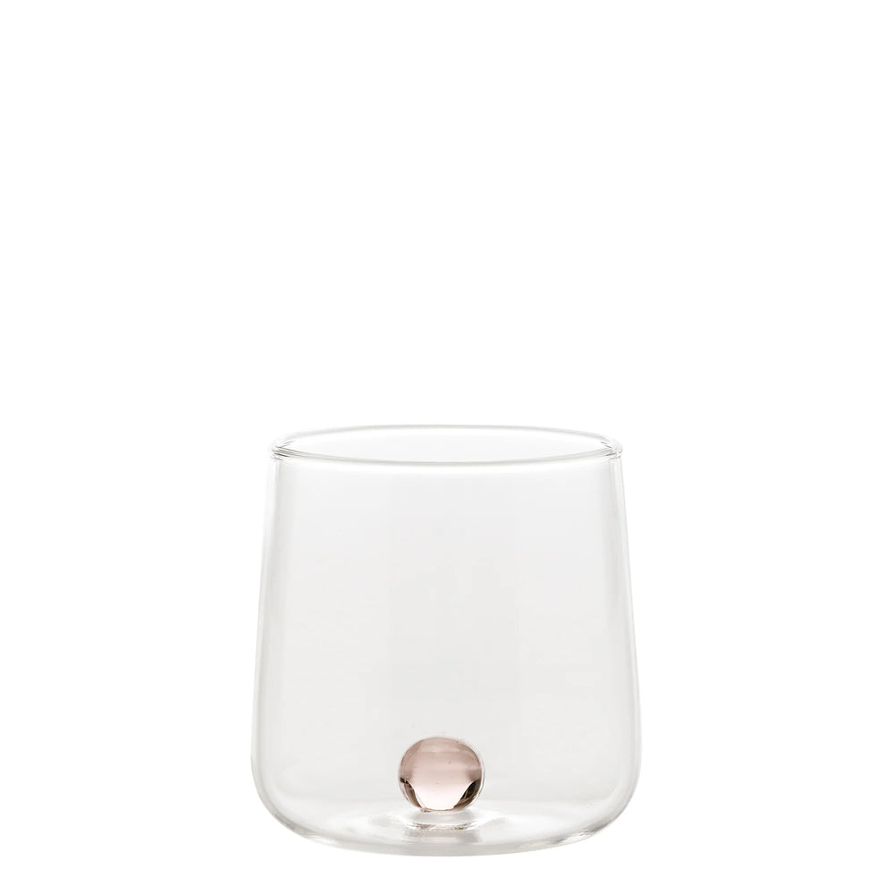Transparant glas met ronde bodem en kleine roze bol op de bodem, neutrale witte achtergrond