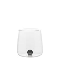 Transparant glas met ronde bodem, kleine glanzende zwarte bol erin, neutrale witte achtergrond.
