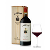 Bottiglia di vino rosso Nipozzano Riserva con etichetta bianca e logo dorato, scatola in legno chiaro e calice con vino rosso.
