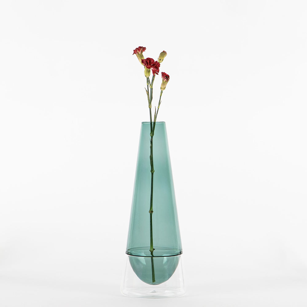 jarrón de vidrio verde transparente con base transparente con tres flores rojas con tallo fino sobre fondo blanco