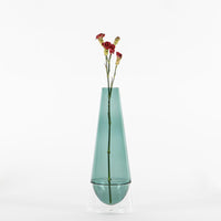 jarrón de vidrio verde transparente con base transparente con tres flores rojas con tallo fino sobre fondo blanco